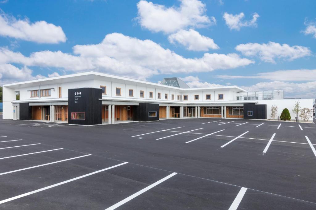 un grand bâtiment blanc avec un parking dans l'établissement Hotel Higashimokoto, à Abashiri