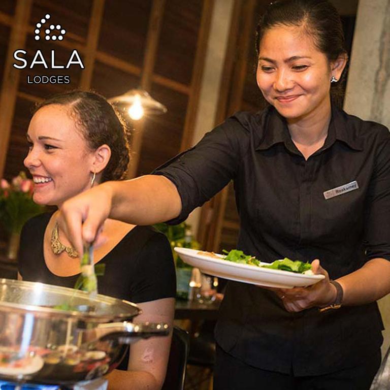 a woman is holding a plate of food at Sala Lodges in Siem Reap