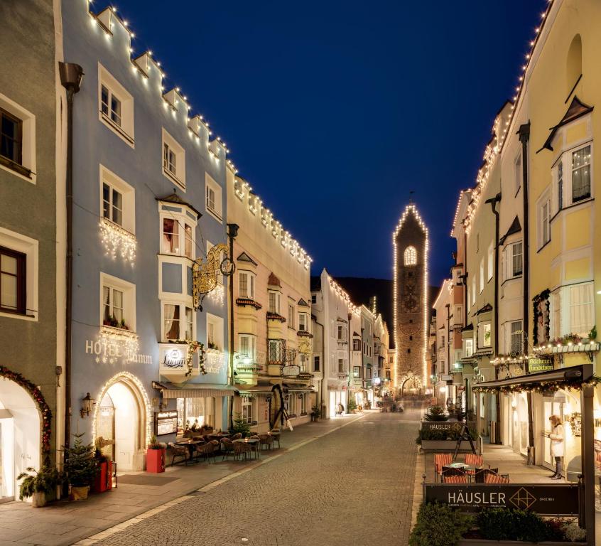 eine leere Straße in der Nacht mit einem Uhrturm in der Unterkunft Hotel Lamm in Sterzing