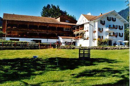 ein großes weißes Gebäude mit einem Grasfeld davor in der Unterkunft Landgasthof Sommerfeld in Pragg-Jenaz