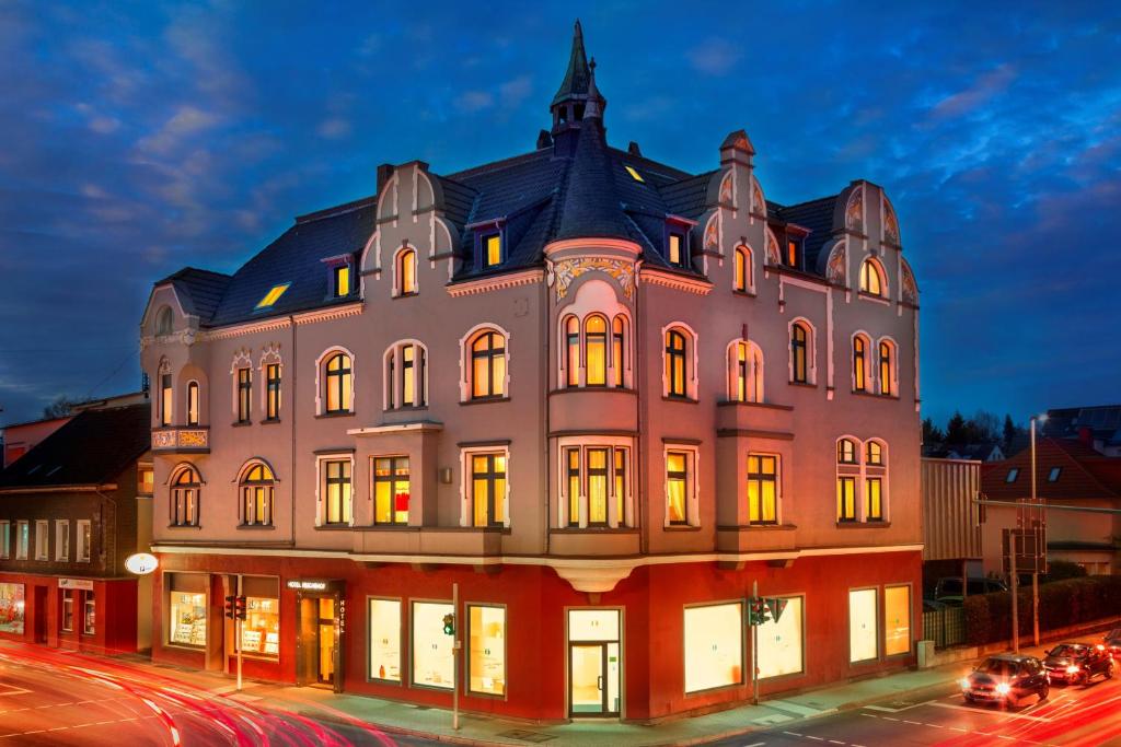 ein großes Gebäude mit nachts eingeschaltetem Licht in der Unterkunft Hotel Reichshof garni in Schwerte