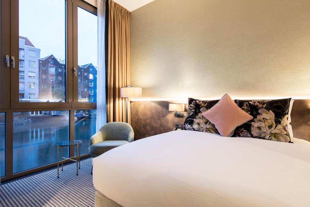 Cette chambre comprend un lit et une grande fenêtre. dans l'établissement Monet Garden Hotel Amsterdam, à Amsterdam