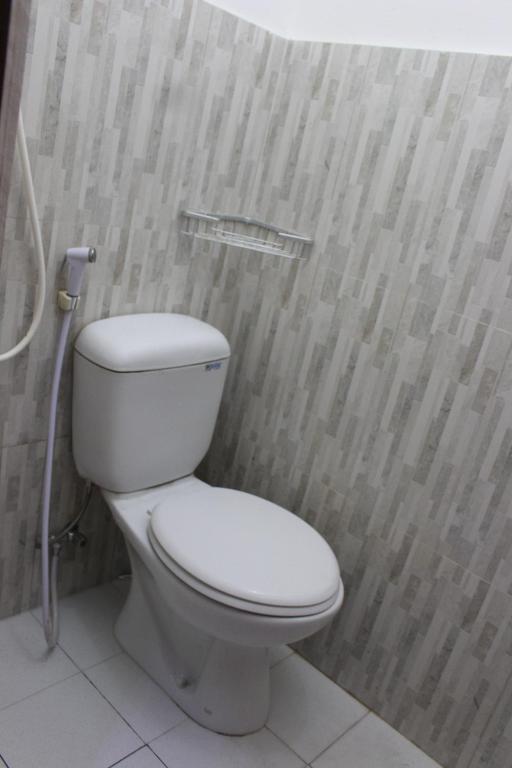 a bathroom with a white toilet and a shower at Rumah Pathuk Syariah Homestay in Yogyakarta