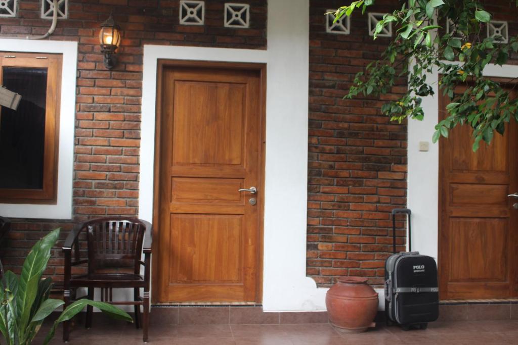 a brick house with two wooden doors and a chair at Rumah Pathuk Syariah Homestay in Yogyakarta