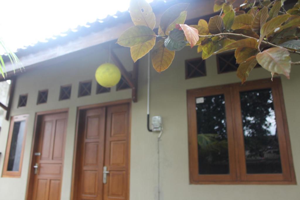 a house with wooden doors and a tree at Rumah Pathuk Syariah Homestay in Yogyakarta