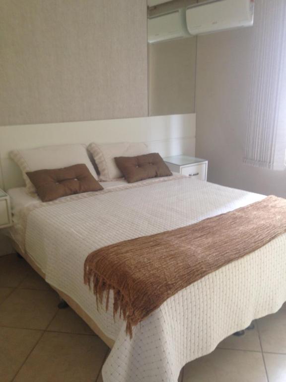 1 dormitorio con 1 cama blanca grande con almohadas marrones en Apartamento Balneário Camboriu, en Balneário Camboriú