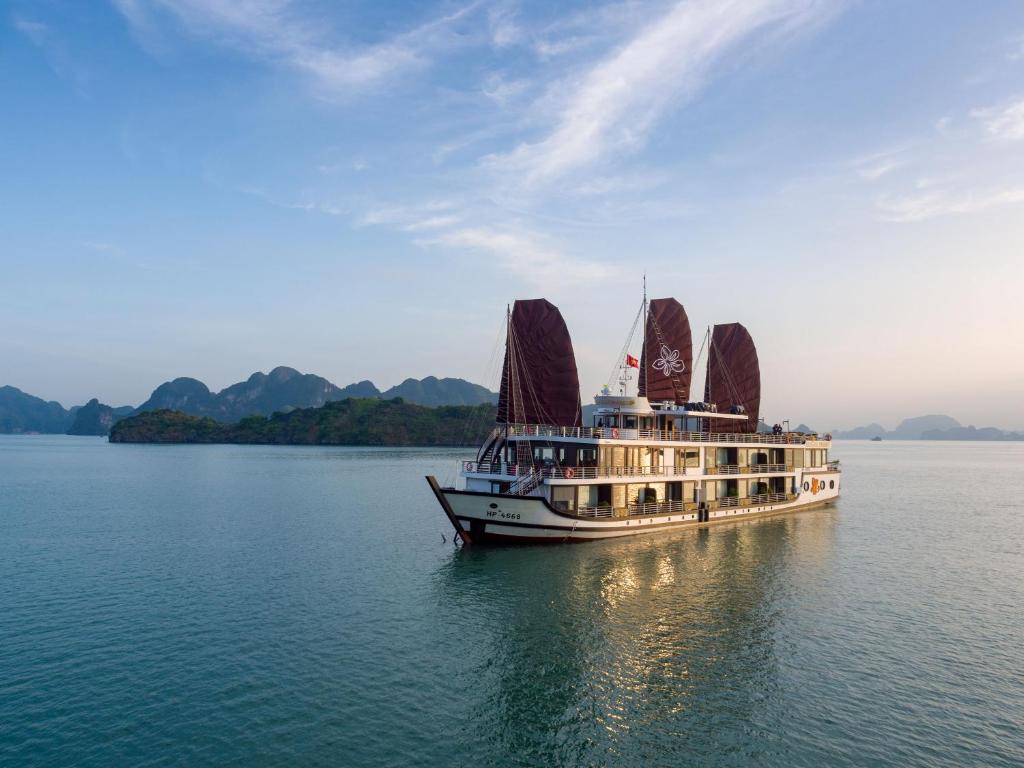 um barco com velas vermelhas na água em Orchid Trendy Cruise em Ha Long