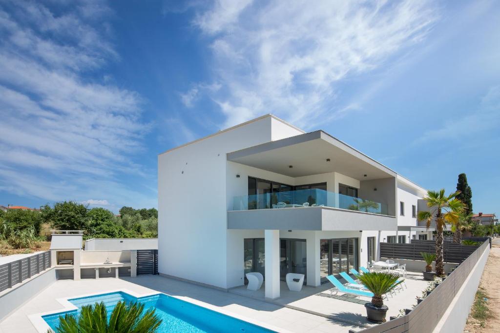 a white villa with a swimming pool and a house at Villa Fasana in Fažana