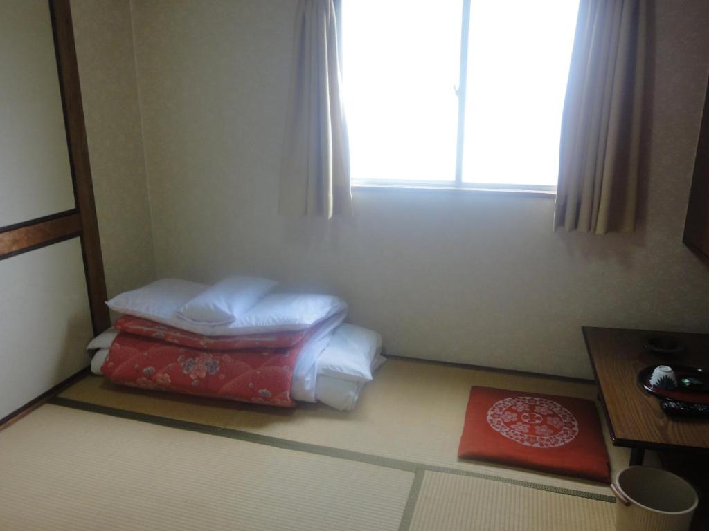 a room with a pile of pillows and a window at Tenryu Ryokan in Hiroshima