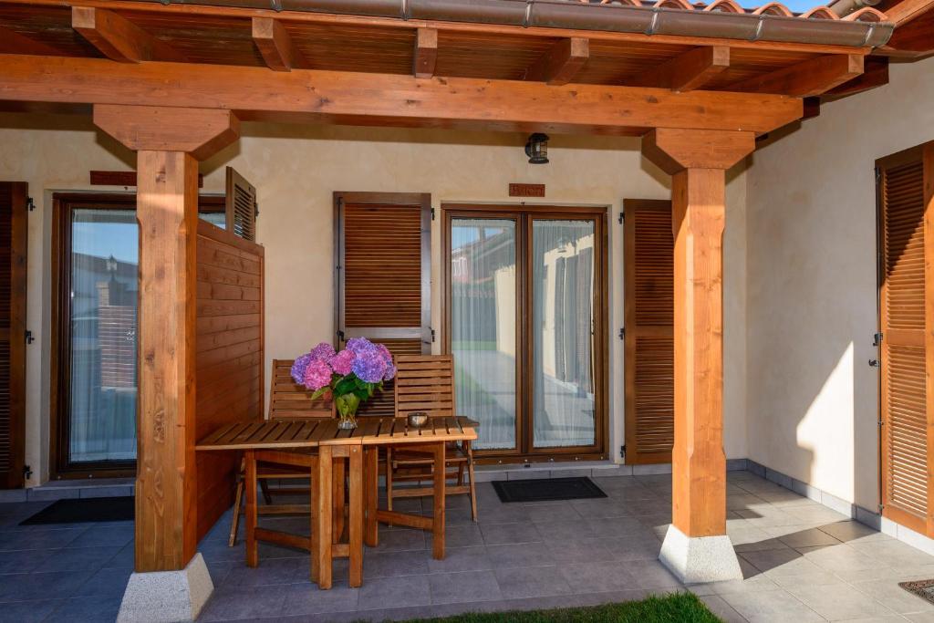a wooden table with a vase of flowers on a patio at Casona de Llanorrozo Apartamentos Rurales in Oviñana