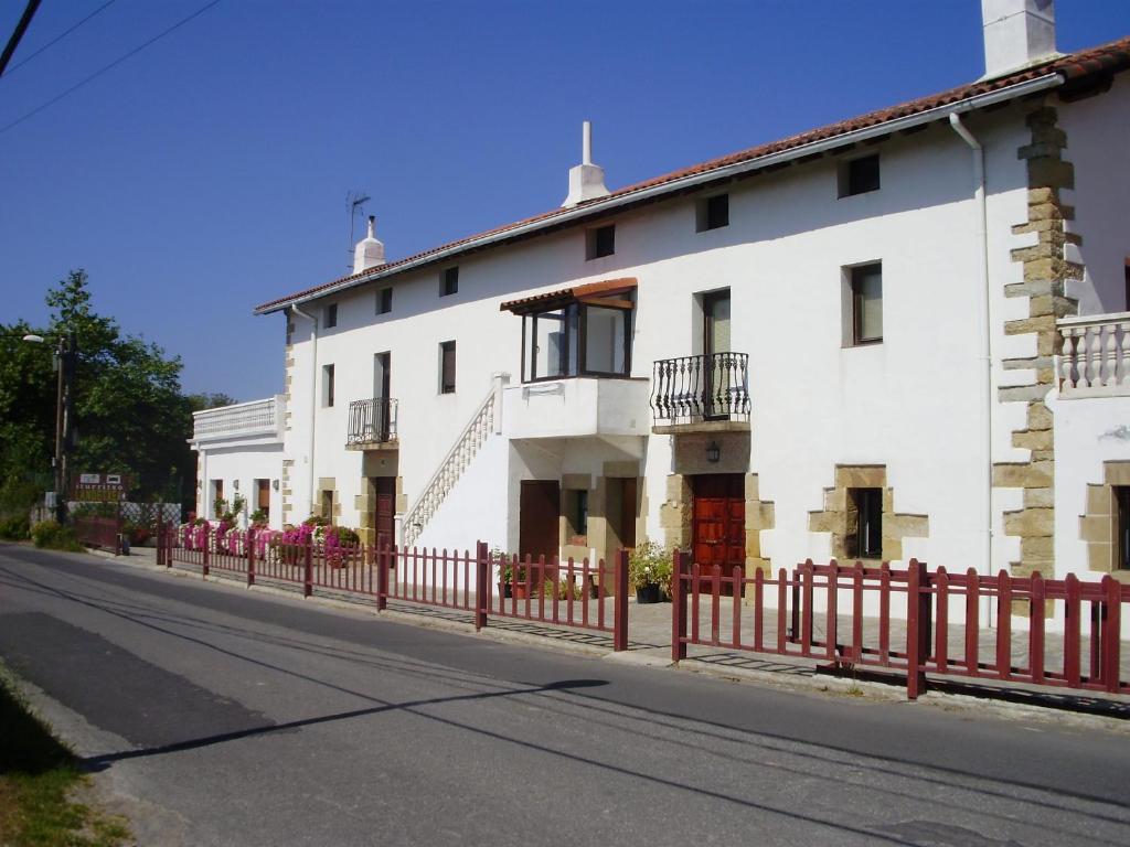 una casa blanca con una valla roja en una calle en Iturritxo Landetxea, en San Sebastián