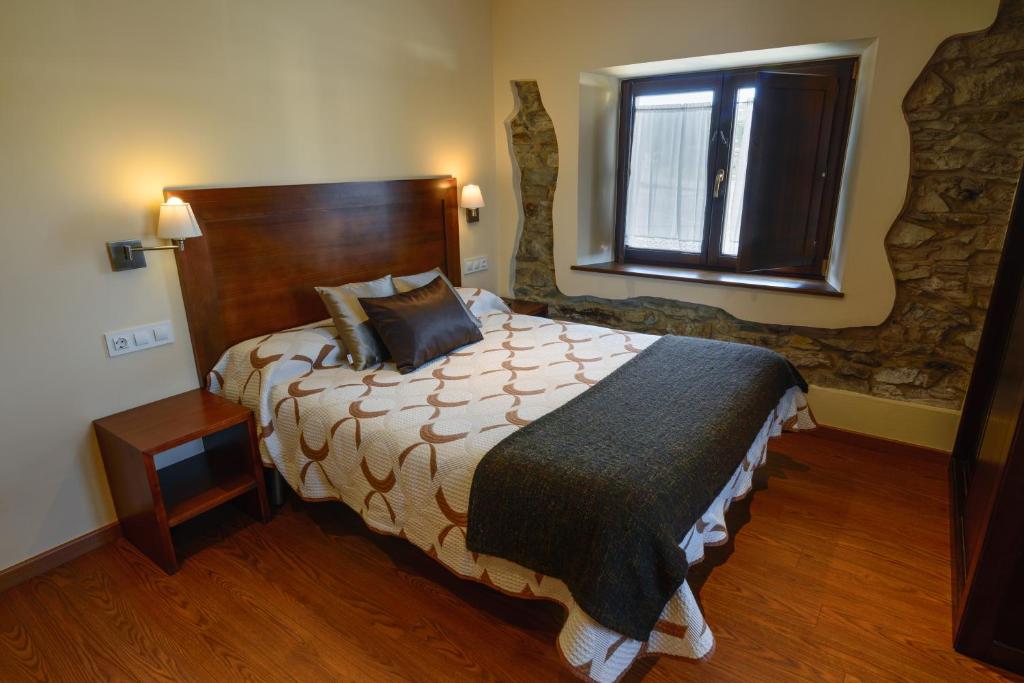 a bedroom with a large bed and a window at Casona de Llanorrozo Apartamentos Rurales in Oviñana