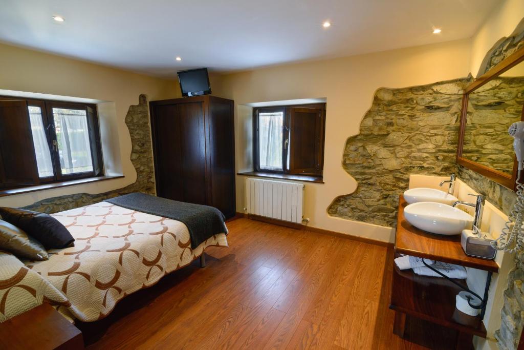 a bedroom with a bed and a sink and a stone wall at Casona de Llanorrozo Apartamentos Rurales in Oviñana