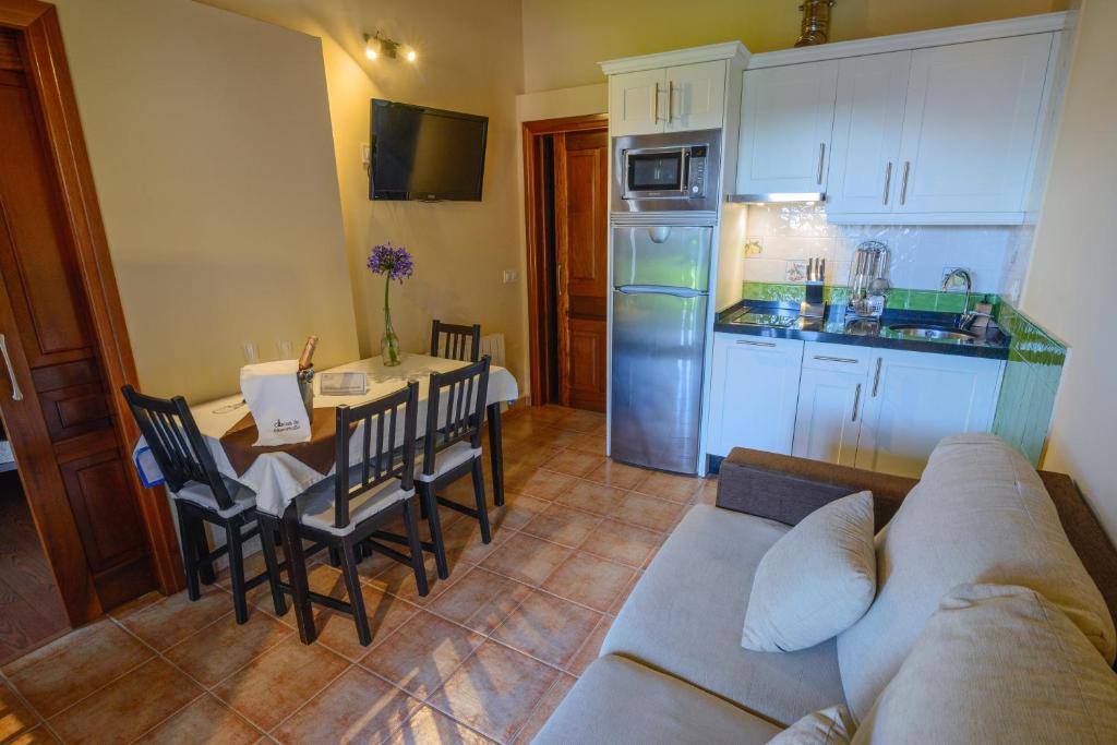 a living room with a couch and a table and a kitchen at Casona de Llanorrozo Apartamentos Rurales in Oviñana