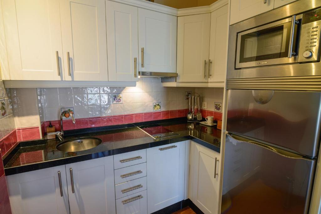 a kitchen with white cabinets and a stainless steel refrigerator at Casona de Llanorrozo Apartamentos Rurales in Oviñana