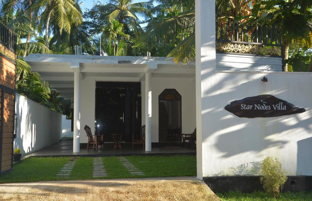 een wit huis met een bord dat zonnemodus villa leest bij Star Nodes Villa in Galle
