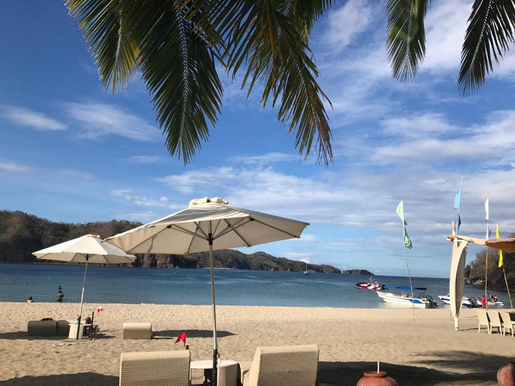 - une plage avec des chaises, un parasol et l'eau dans l'établissement Creys condo at Pico de Loro Cove, à Nasugbu