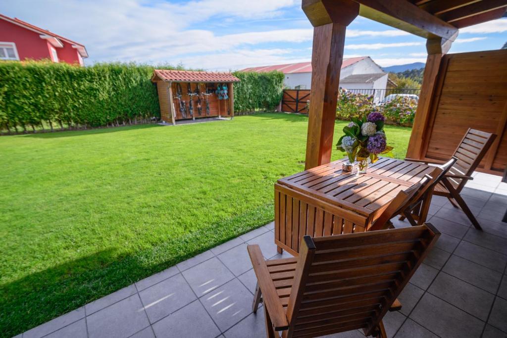 a wooden table and chairs on a patio with a yard at Casona de Llanorrozo Apartamentos Rurales in Oviñana