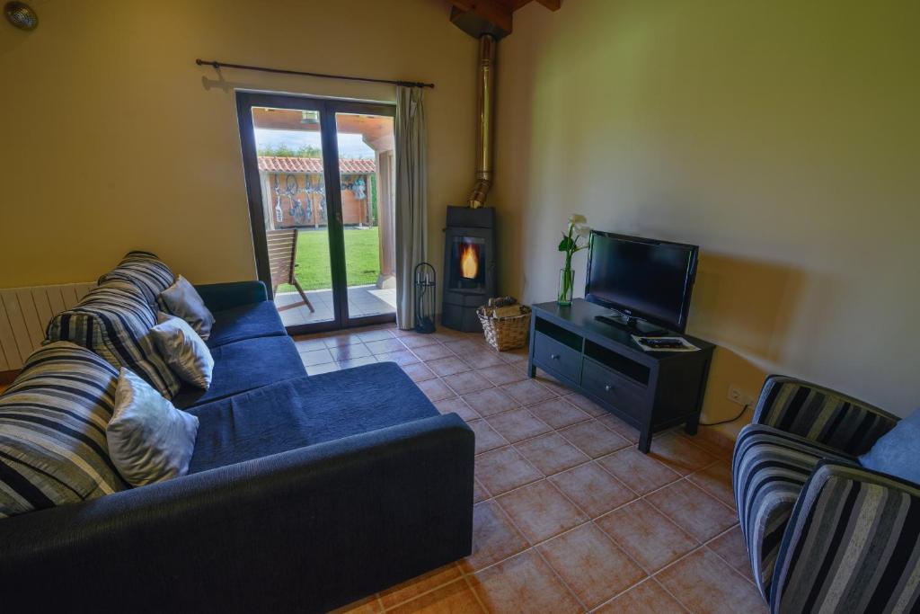 a living room with a blue couch and a tv at Casona de Llanorrozo Apartamentos Rurales in Oviñana