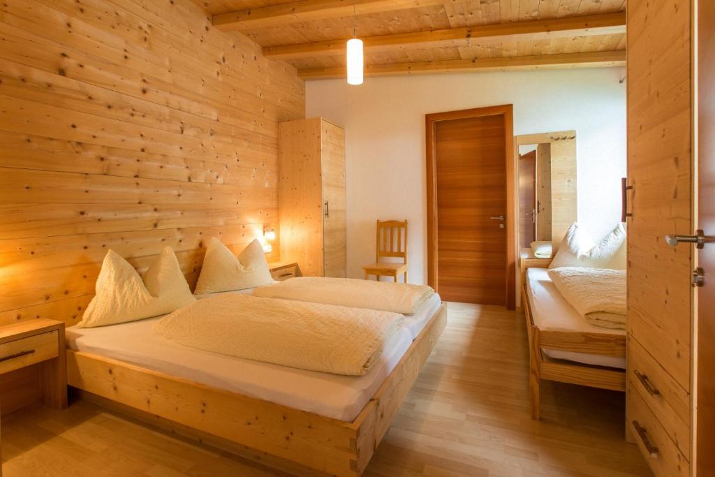 a bedroom with two beds and a wooden wall at Morigglhof in Malles Venosta
