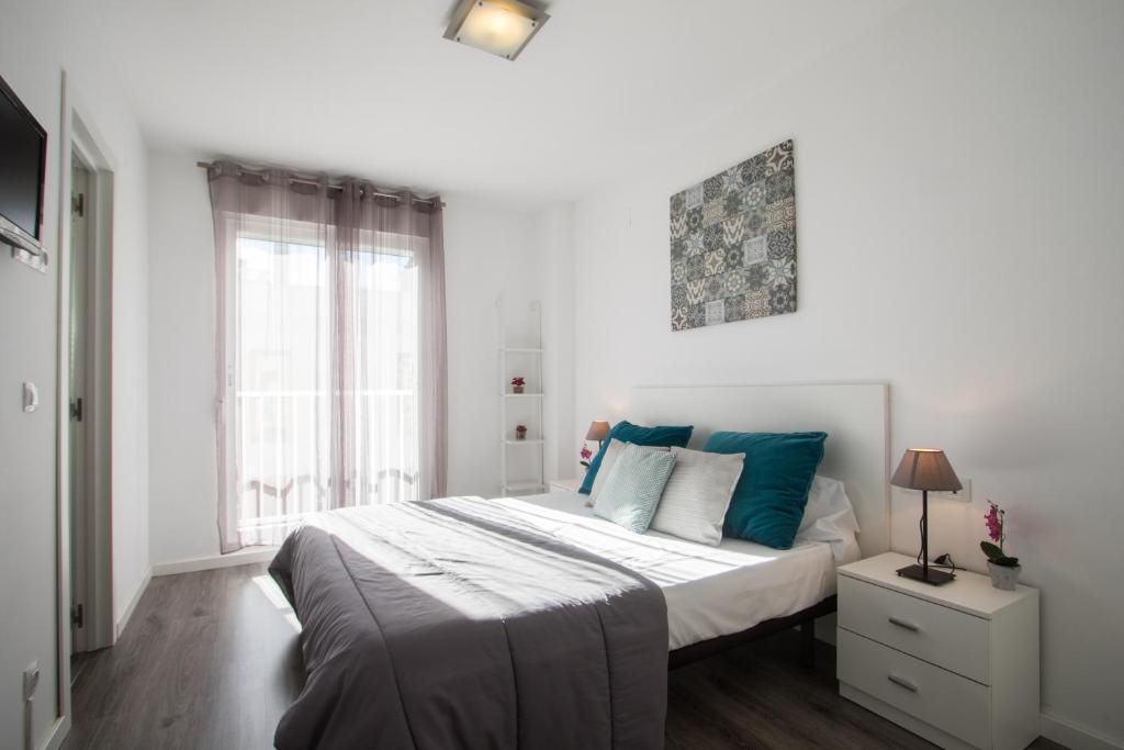 um quarto branco com uma cama grande e almofadas azuis em Flatsforyou Turia em Valência