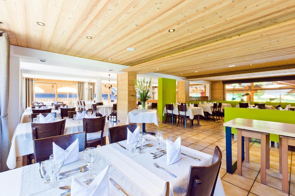 a dining room with white tables and chairs at Hotel Les Bruyères in Morzine