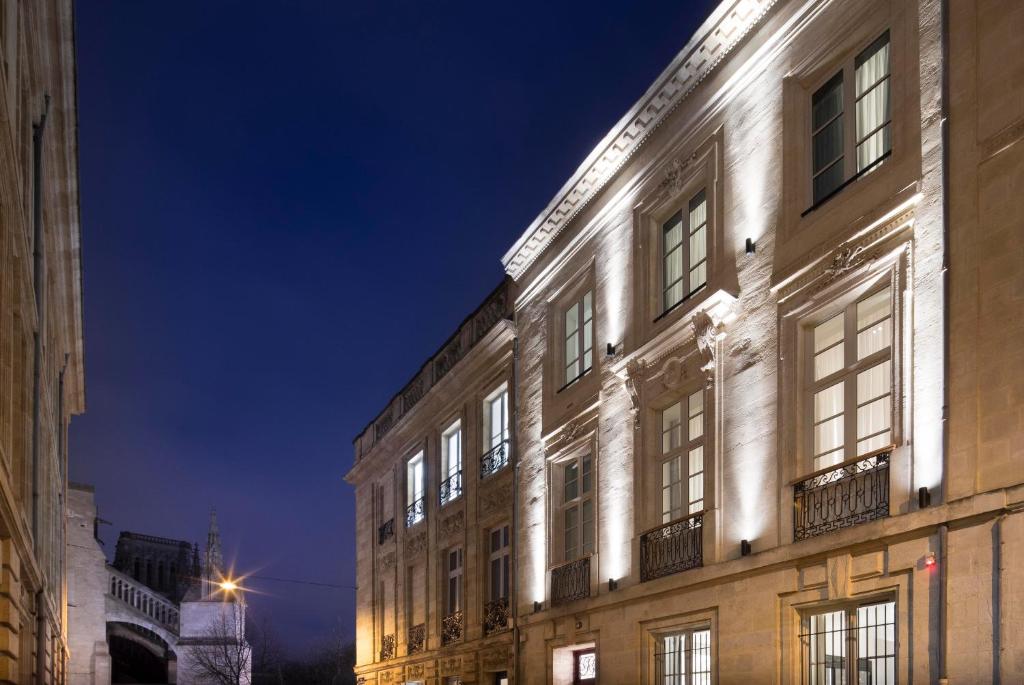 a building with lights on the side of it at night at Hôtel Cardinal Bordeaux Centre in Bordeaux