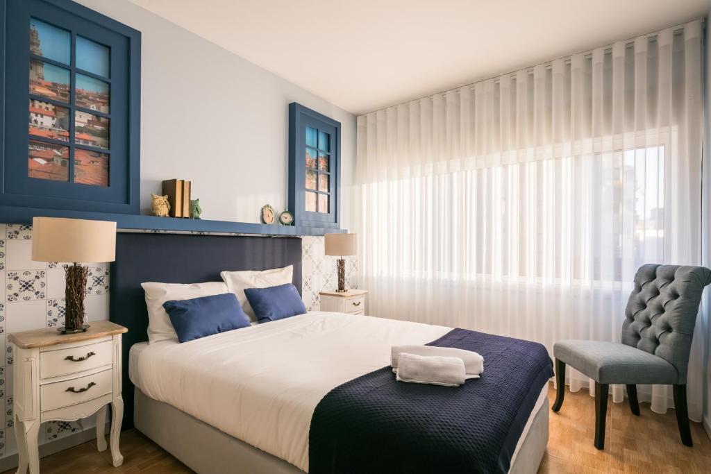 - une chambre avec un grand lit et une chaise dans l'établissement Camarinha Oporto Apartments, à Porto