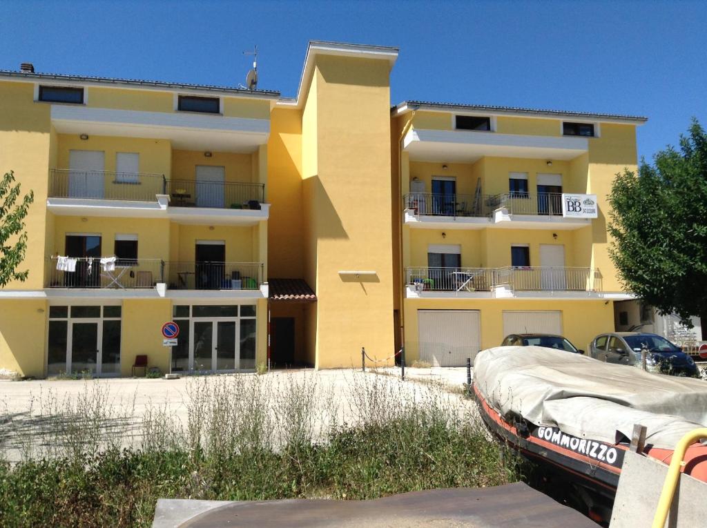 żółty budynek z samochodem zaparkowanym przed nim w obiekcie green coppito w mieście Coppito
