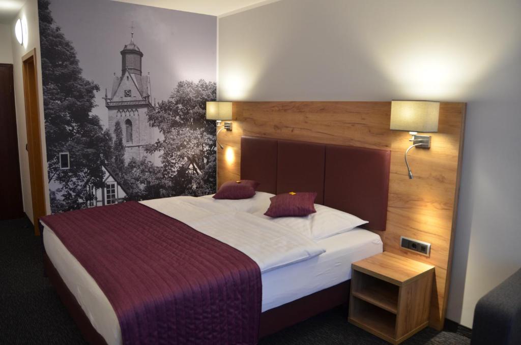 a bedroom with a bed with a painting on the wall at Hotel Touric in Korbach
