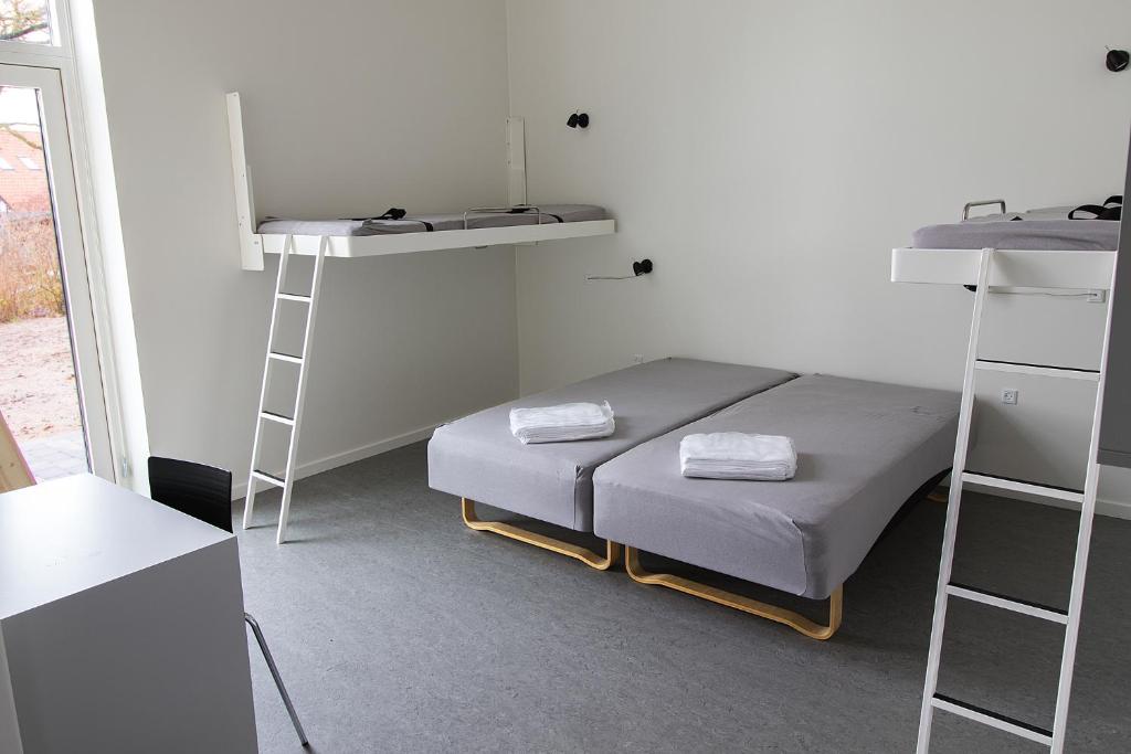 Zimmer mit einem Bett, 2 Etagenbetten und einer Leiter in der Unterkunft Hostel Brønderslev in Brønderslev