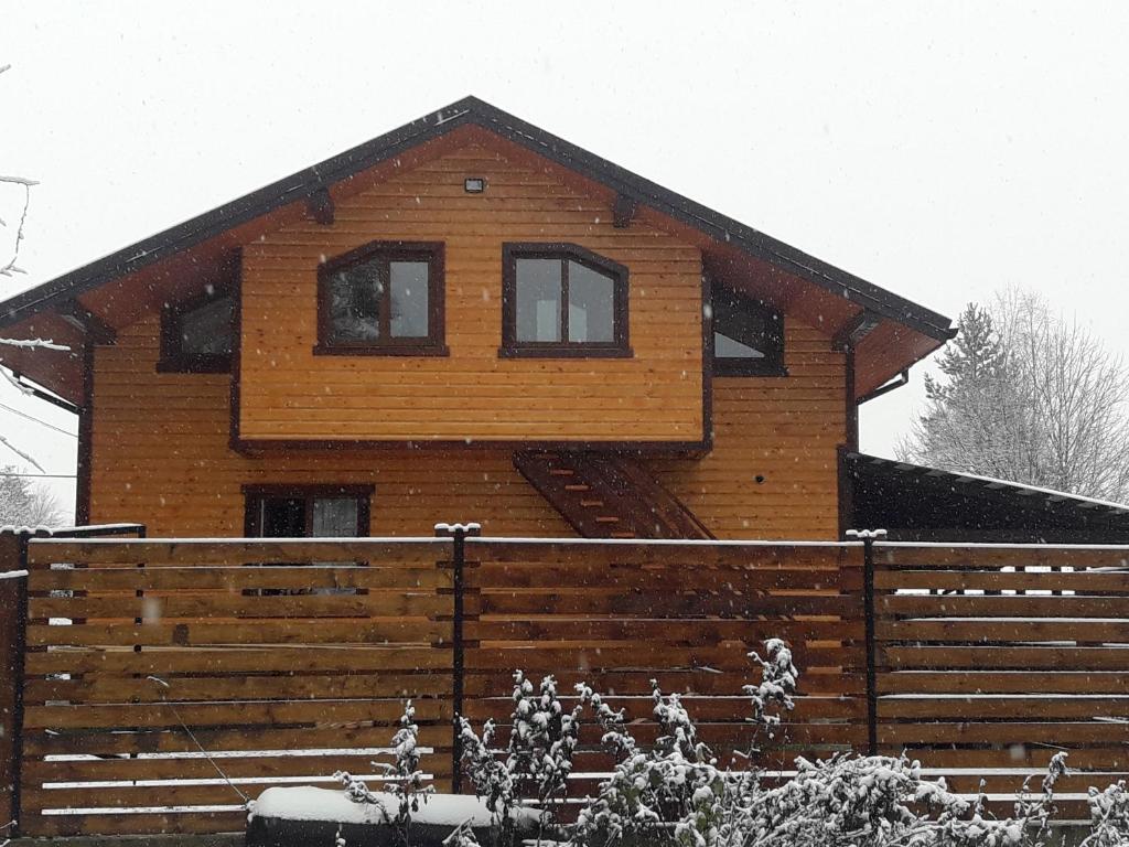 ein Holzhaus mit einem Zaun davor in der Unterkunft Чан-садиба Гуцульська пісня in Mykulytschyn