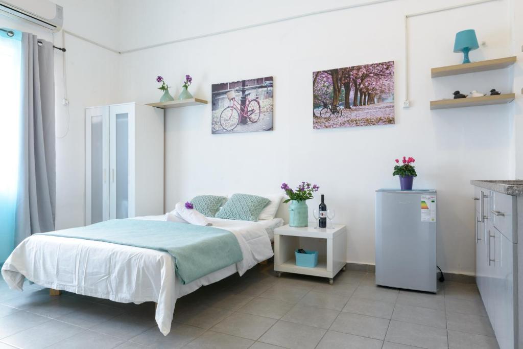a white bedroom with a bed and a refrigerator at Hacarmel Apartment in Tel Aviv