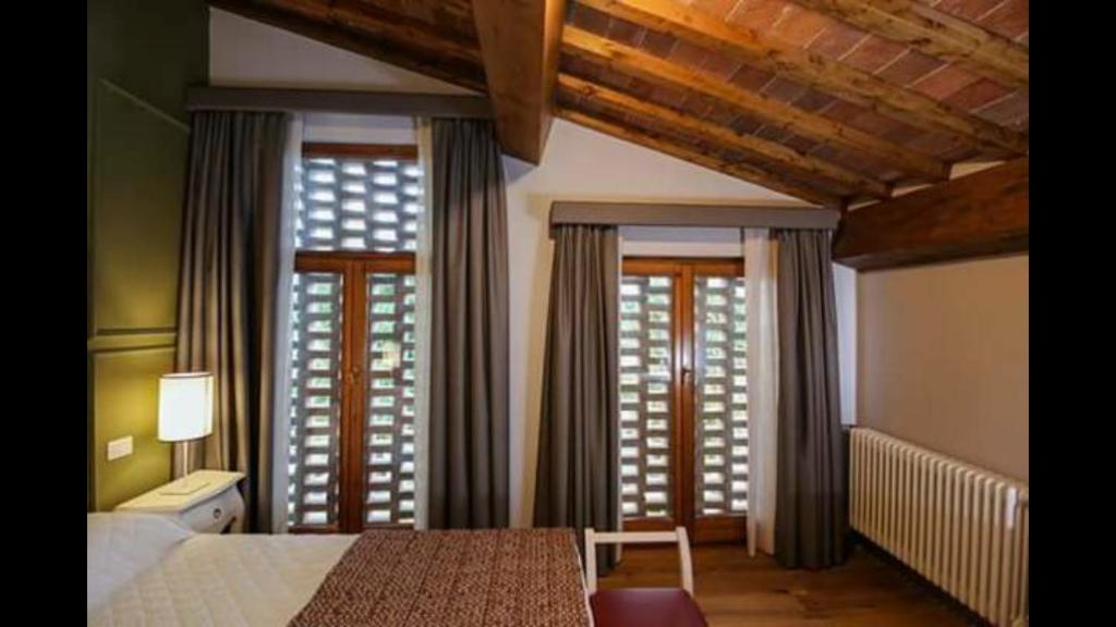 - une chambre avec un lit et 2 fenêtres avec des rideaux dans l'établissement Agriturismo Casanova di Nardini, à Scandicci