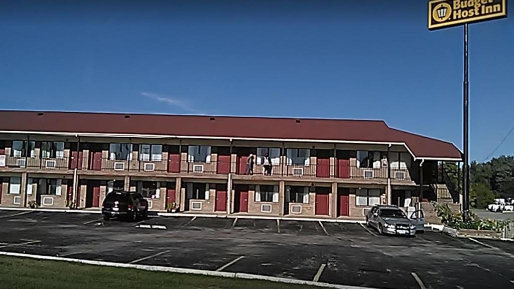 a large building with cars parked in a parking lot at Budget Host Inn in Winchester