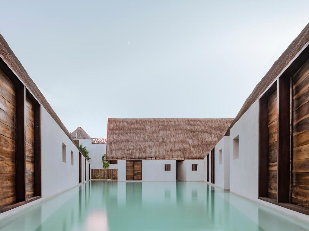 an empty courtyard of a house with a thatched roof at Hotel Boutique Punta Caliza - Adults Oriented in Holbox Island