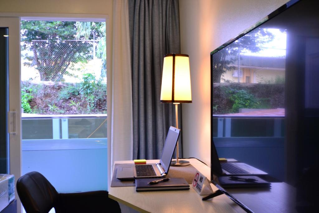 a room with a desk with a laptop and a window at Quints Travelers Inn in Willemstad