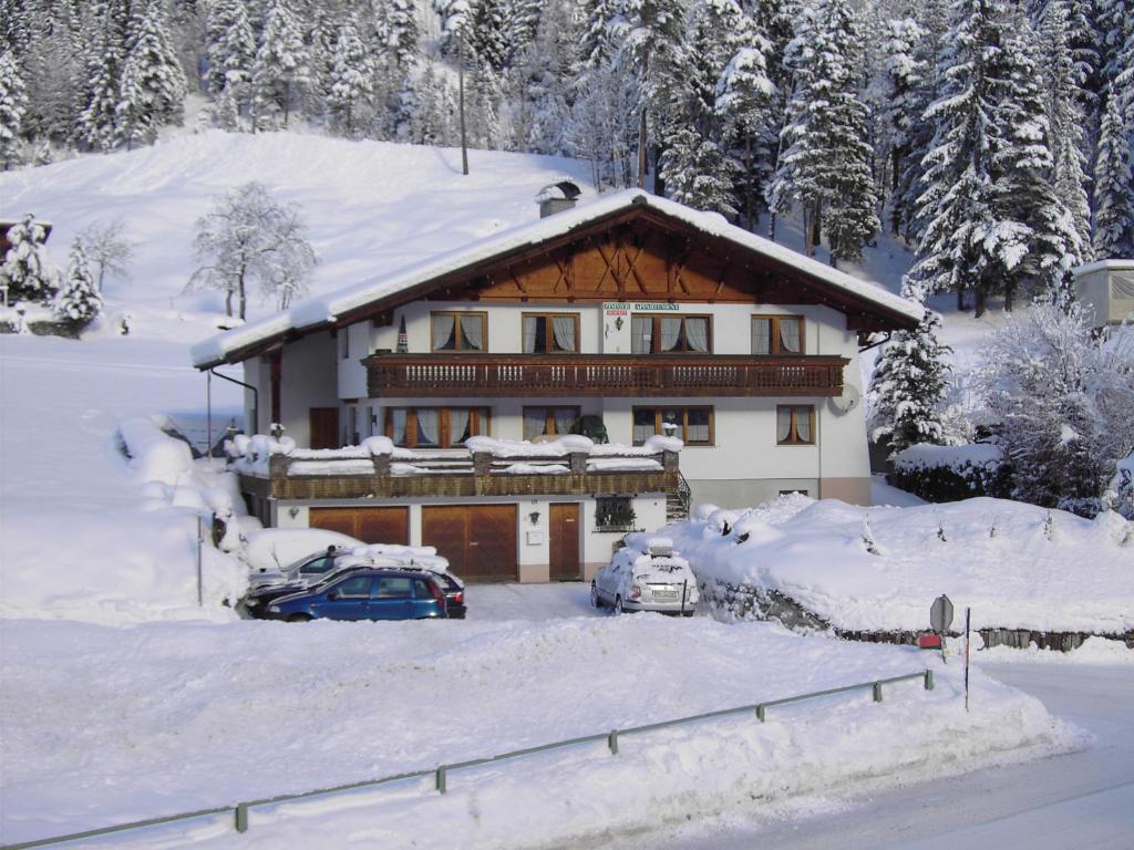 a snow covered house with cars parked in front of it at Pension Seeberger in Wald am Arlberg