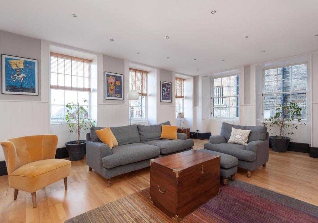 ein Wohnzimmer mit einem Sofa, Stühlen und Fenstern in der Unterkunft Parliament Sq (apt 3) Royal Mile in Edinburgh