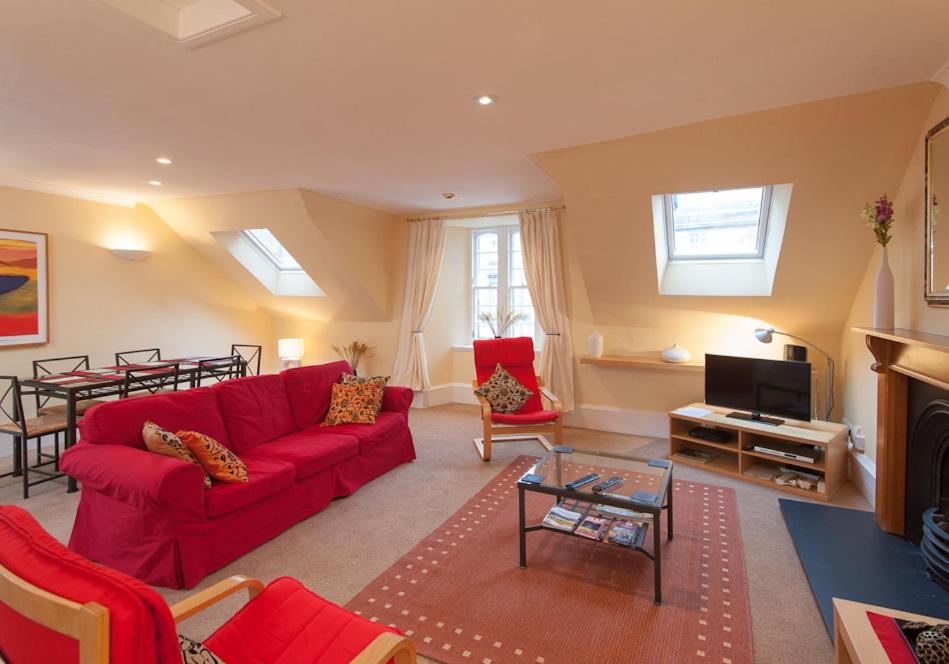 uma sala de estar com um sofá vermelho e uma mesa em Parliament Sq (apt 5) Royal mile em Edinburgo
