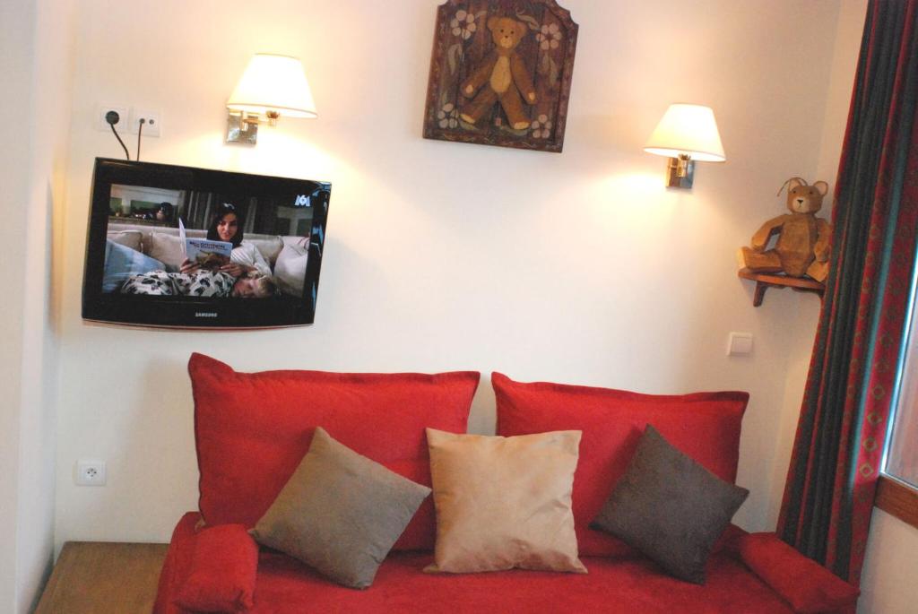 a living room with a red couch with a tv on the wall at Appartement La Plagne Soleil in La Plagne