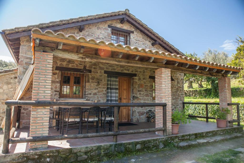 a small stone house with a porch and a deck at Casa Rural El Pilar in Acebo