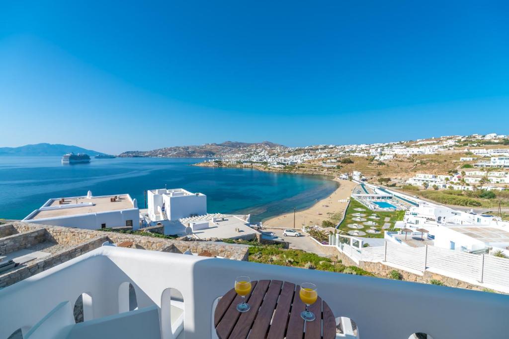 a large blue and white building next to a body of water at Cape Mykonos in Mikonos