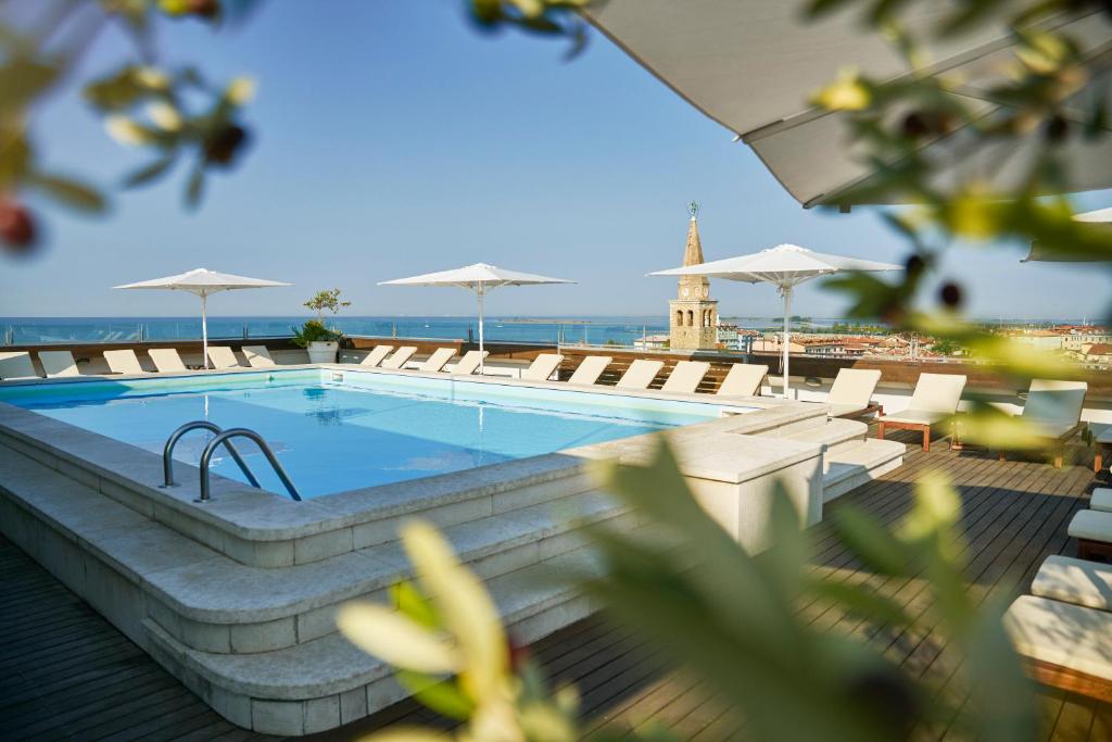 a swimming pool with chairs and umbrellas on a building at Hotel Fonzari in Grado