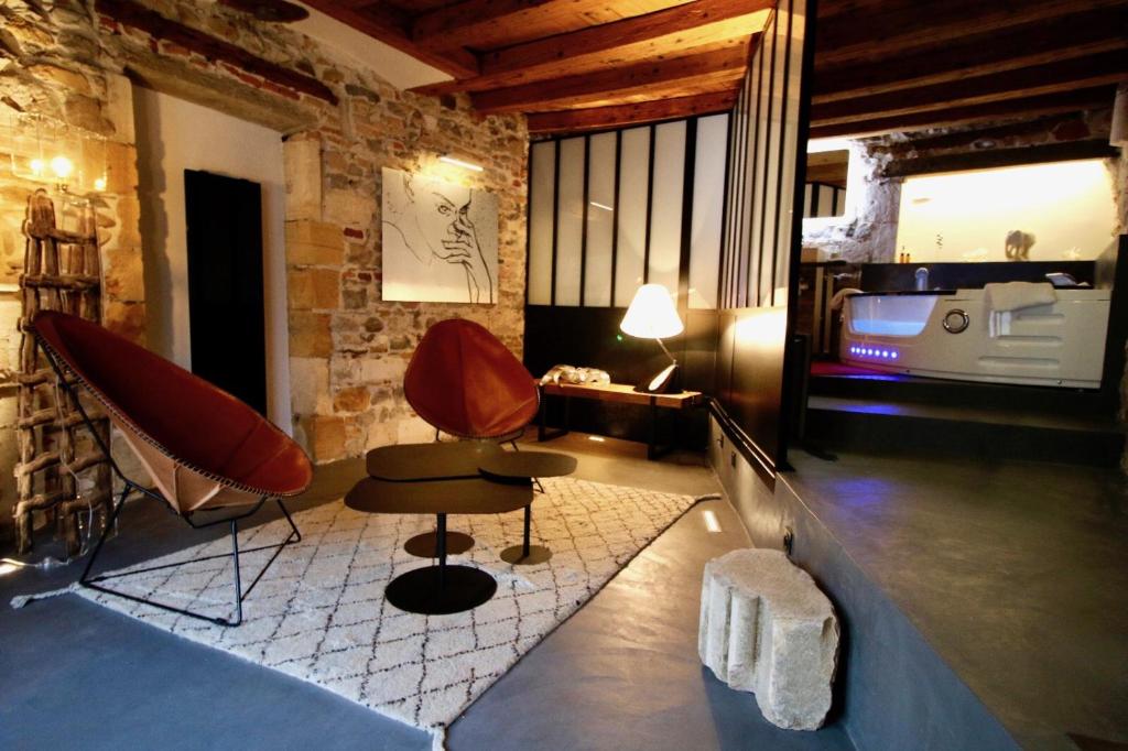 リヨンにあるLe Clos de Sainte Croixの椅子2脚、テーブル1台、ベッド1台が備わる客室です。