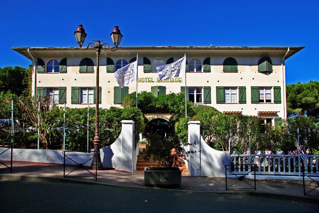 een groot wit gebouw met vlaggen ervoor bij Hotel Ermitage in Saint-Tropez