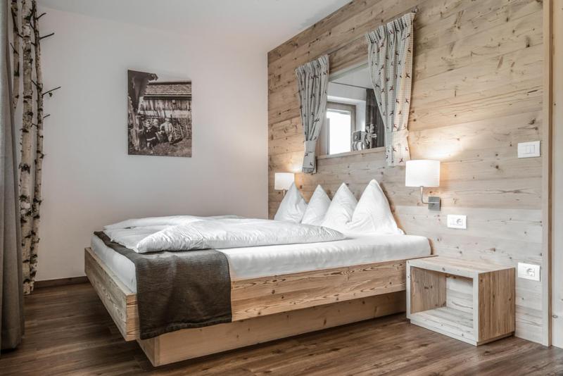 a bedroom with a large bed with a wooden wall at Haus Spielbichl in San Lorenzo di Sebato