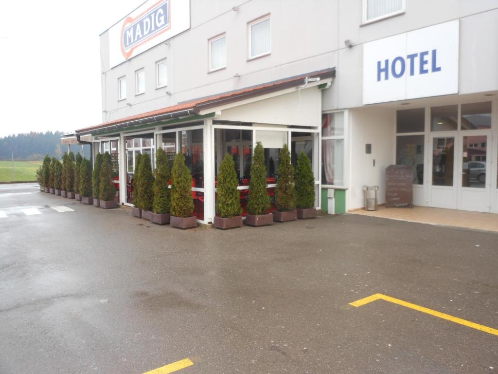 a hotel with a row of trees in a parking lot at Hotel Klek in Ogulin