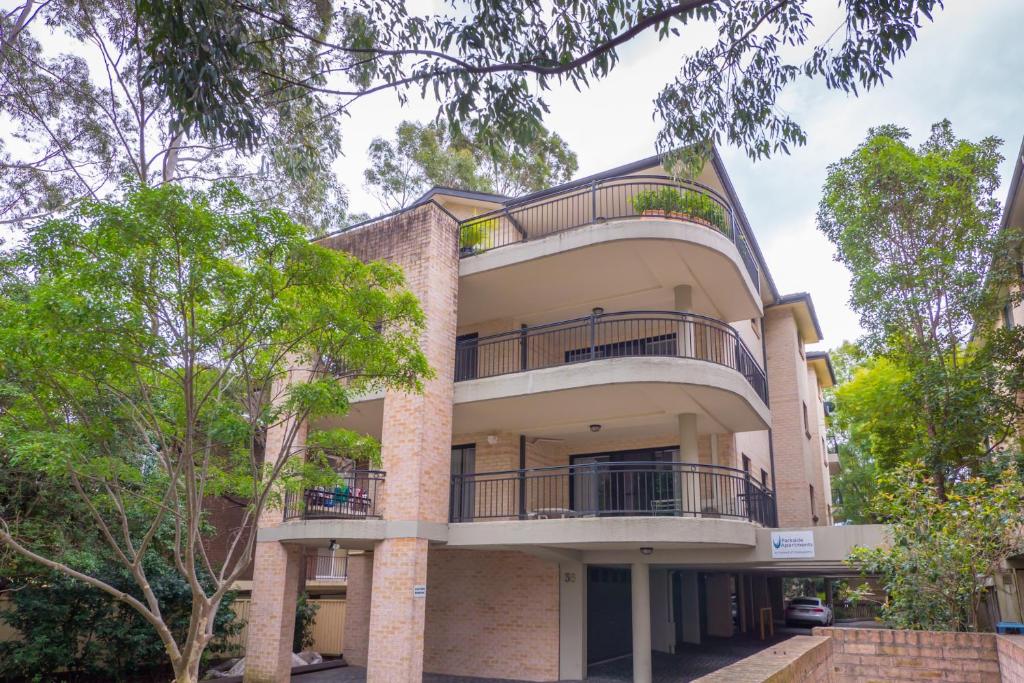 un edificio de apartamentos con balcones y árboles en Parkside Apartments Parramatta, en Sídney