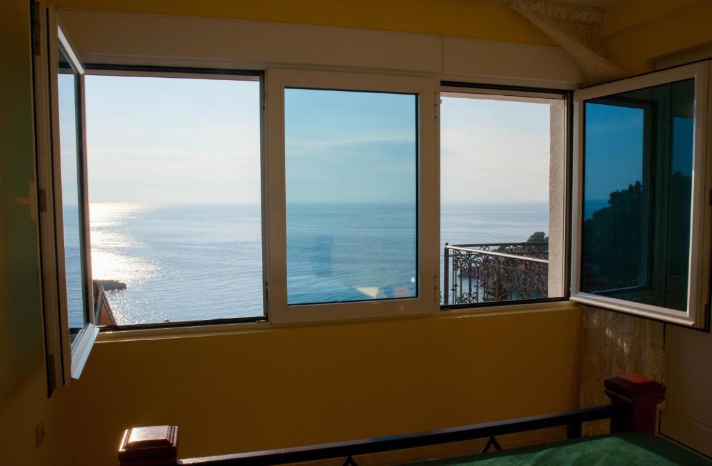 a room with three windows with a view of the ocean at Villa Edelweiss in Sveti Stefan